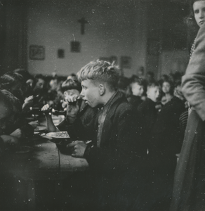 876784 Afbeelding van een grote groep kinderen die aan het eten is in een klaslokaal van de Piusschool (Oudegracht 33) ...
